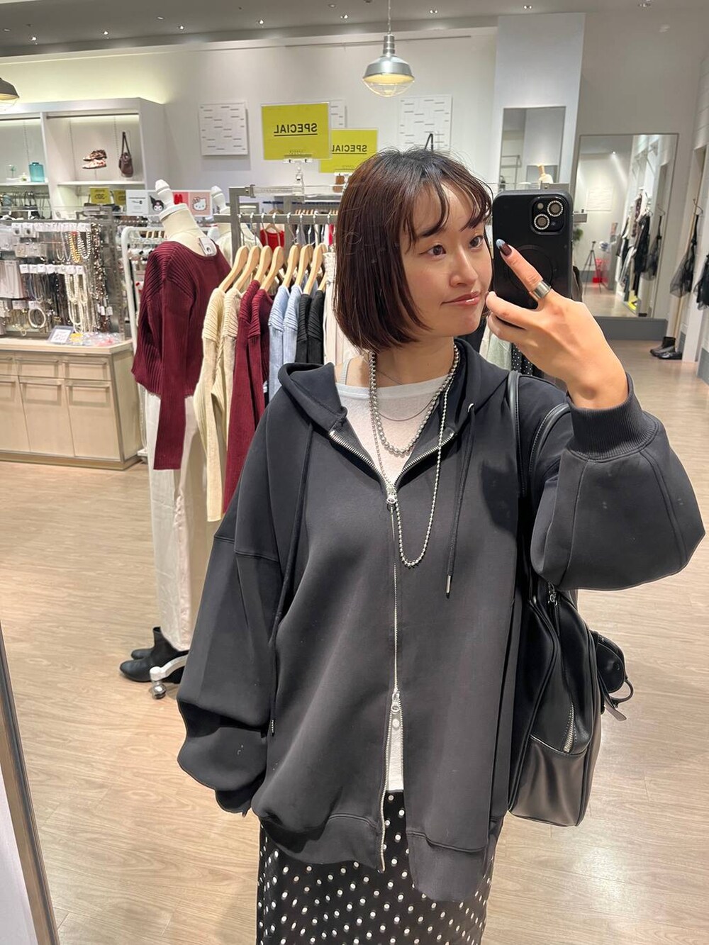 ブラック系のスカート、ブラック系のパーカー、ホワイト系のTシャツ/カットソーを着用したレディースの秋コーディネートの3枚目の写真