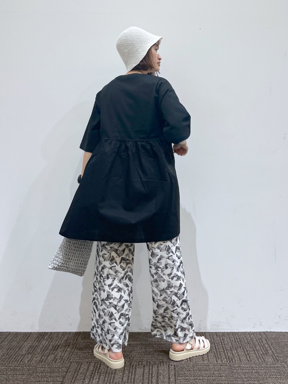 ゴールド系のバッグ、ブラック系のTシャツ/カットソー、ホワイト系のその他パンツを着用したレディースの春コーディネートの3枚目の写真