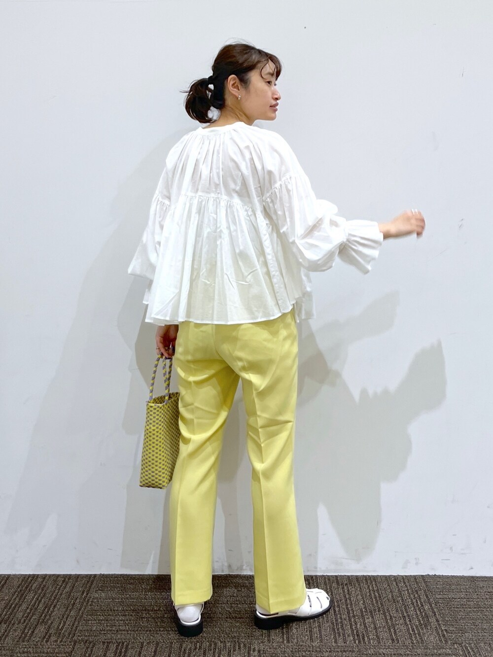イエロー系のスラックス、パープル系のかごバッグ、ホワイト系のシャツ/ブラウスを着用したレディースの春コーディネートの3枚目の写真