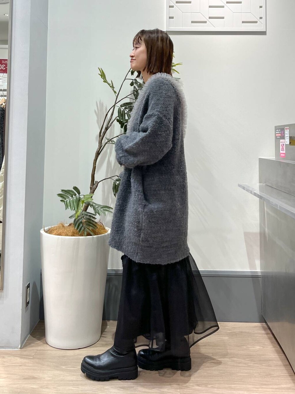 グレー系のチュニック、ブラック系のブーツ、ブラック系のショルダーバッグを着用したレディースの冬コーディネートの3枚目の写真