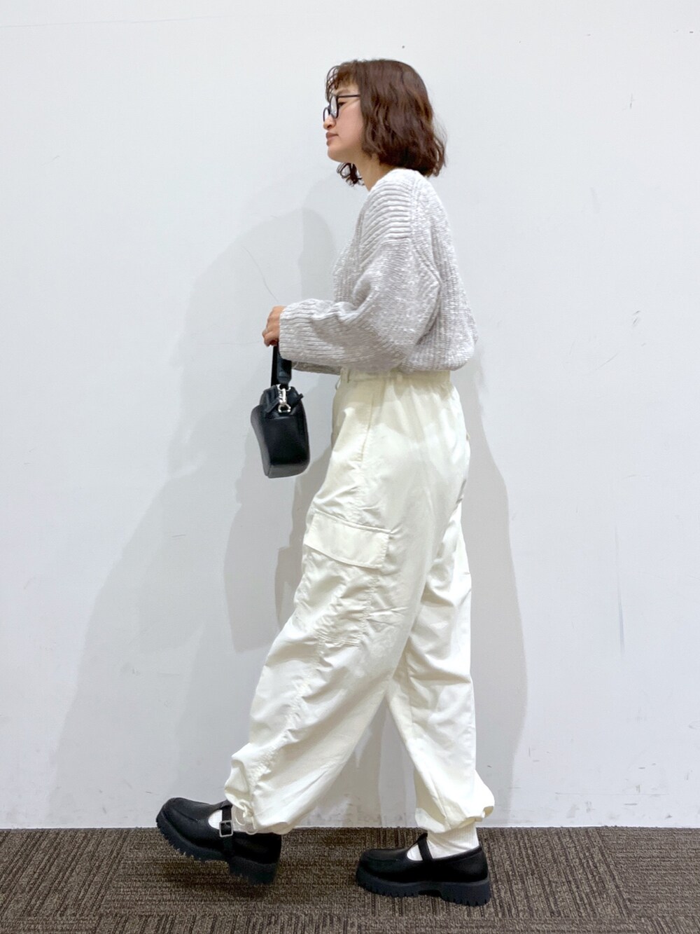 ブラック系のローファー、ブラック系のショルダーバッグ、ホワイト系のカーゴパンツを着用したレディースの冬コーディネートの2枚目の写真