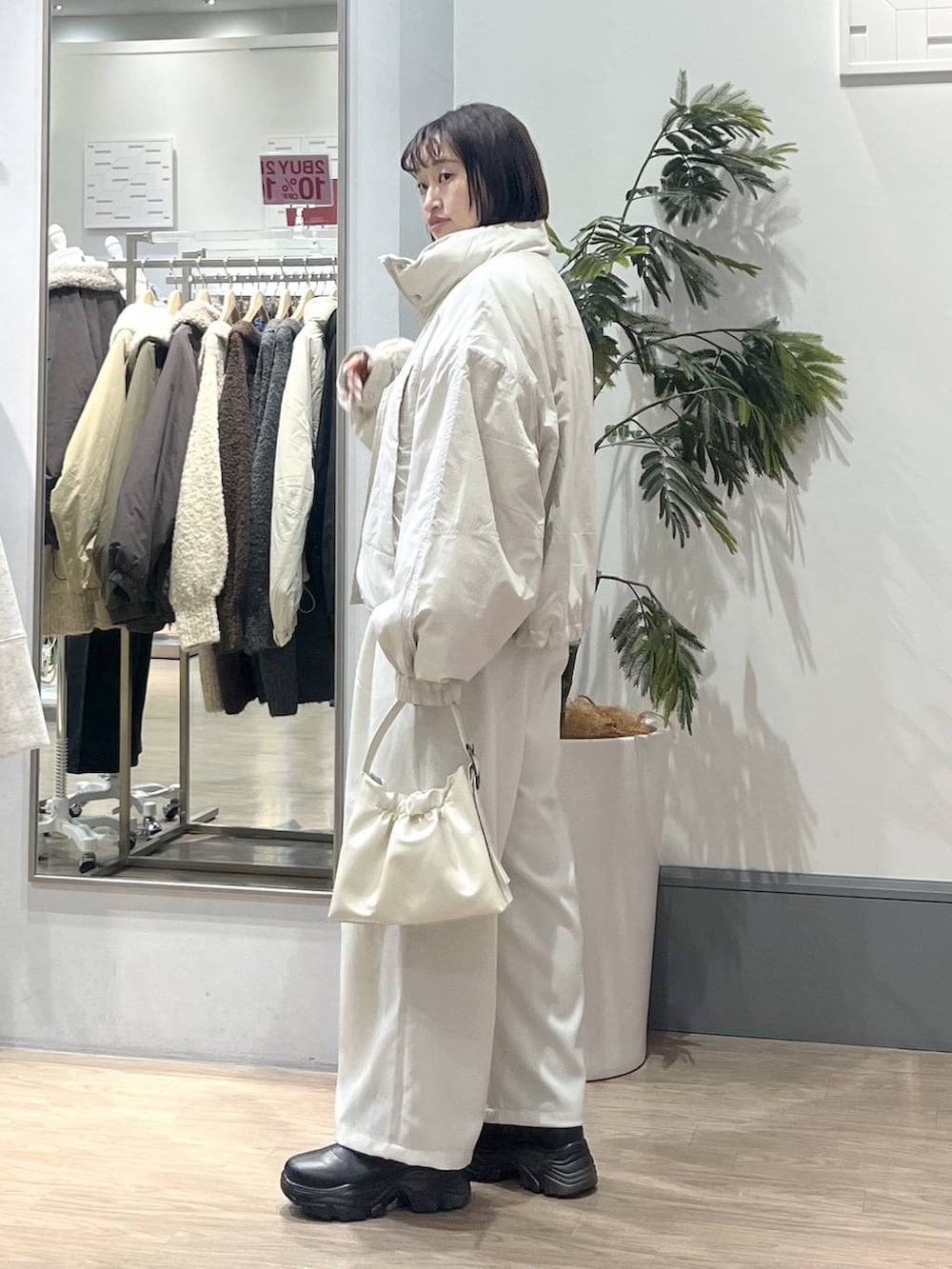 ホワイト系のその他アウター、ブラック系のブーツ、ホワイト系のニット/セーターを着用したレディースの冬コーディネートの3枚目の写真