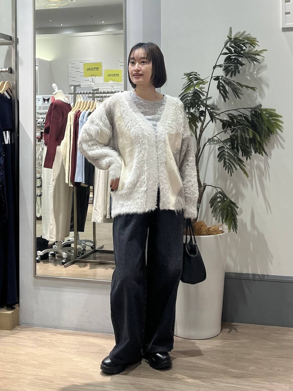 ブラック系のブーツ、ホワイト系のカーディガン/ボレロ、ホワイト系のTシャツ/カットソーを着用したレディースの秋コーディネートの2枚目の写真