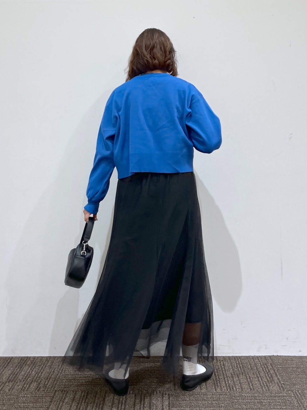 ブルー系のトップス、ブラック系のスカート、ホワイト系のトップスを着用したレディースの春コーディネートの3枚目の写真