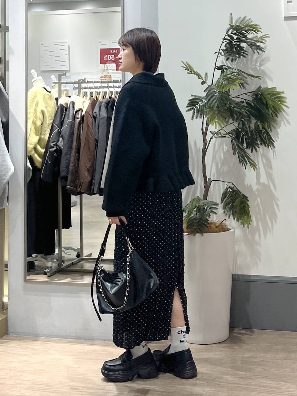 ブラック系のショルダーバッグ、ブラック系のローファー、ブラック系のスカートを着用したレディースの冬コーディネートの4枚目の写真