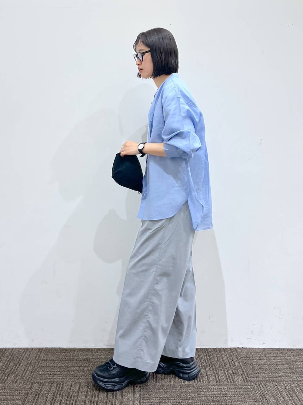 グレー系のスラックス、ブラック系のスニーカー、ホワイト系のTシャツ/カットソーを着用したレディースの春コーディネートの3枚目の写真