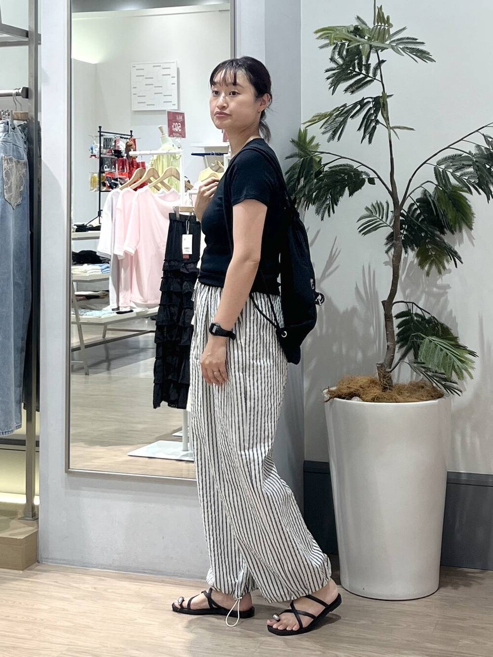 ブラック系のTシャツ/カットソー、ブラック系のサンダル、ブラック系のバックパック/リュックを着用したレディースの夏コーディネートの2枚目の写真