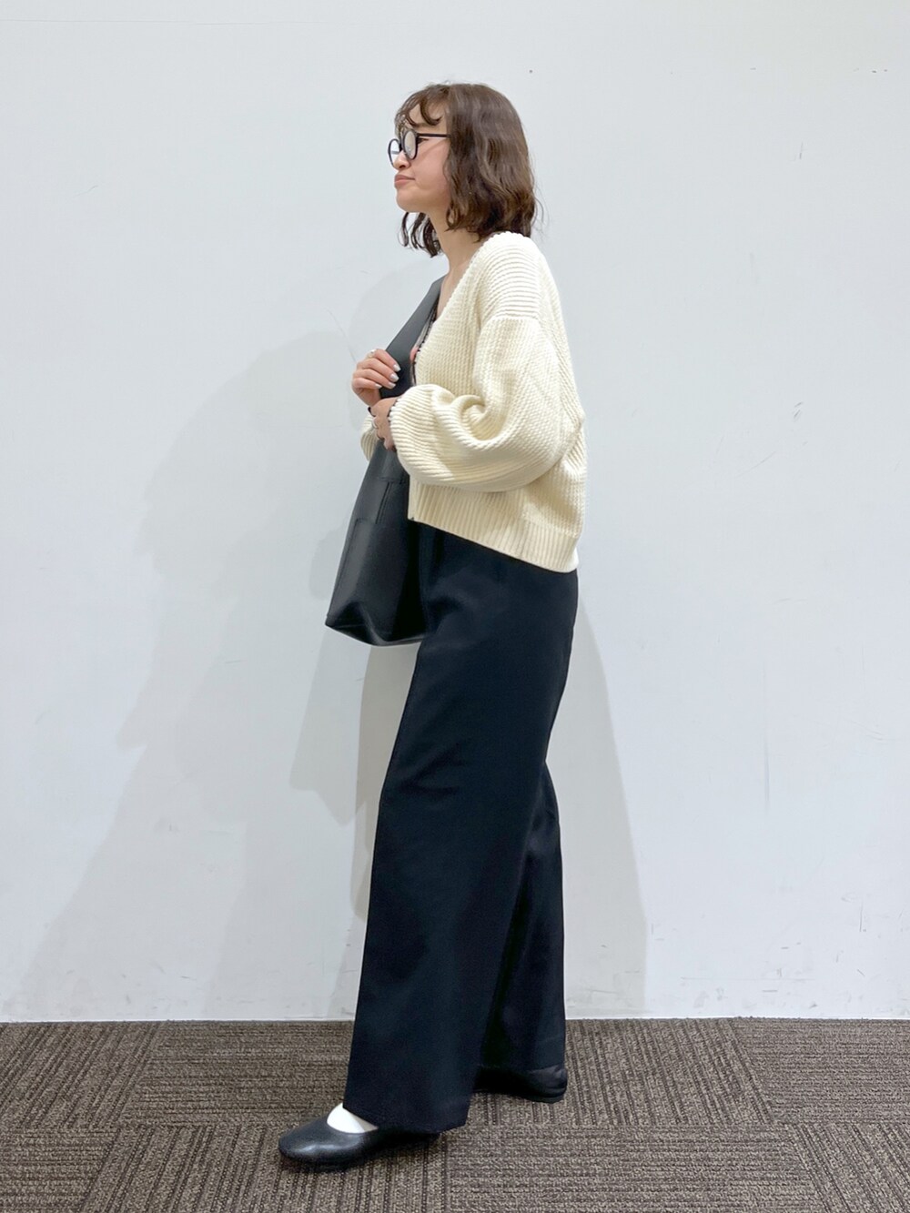 ブラック系のパンツ、ホワイト系のカーディガン/ボレロ、ホワイト系のトップスを着用したレディースの春コーディネートの2枚目の写真