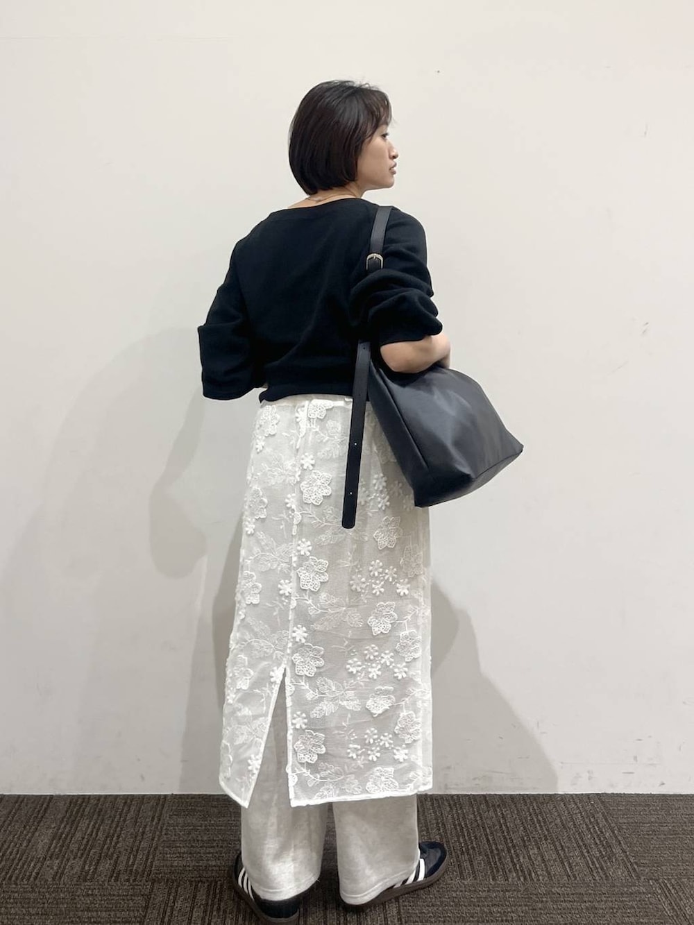 ブラック系のショルダーバッグ、グレー系のスウェットパンツ、ホワイト系のスカートを着用したレディースの春コーディネートの5枚目の写真