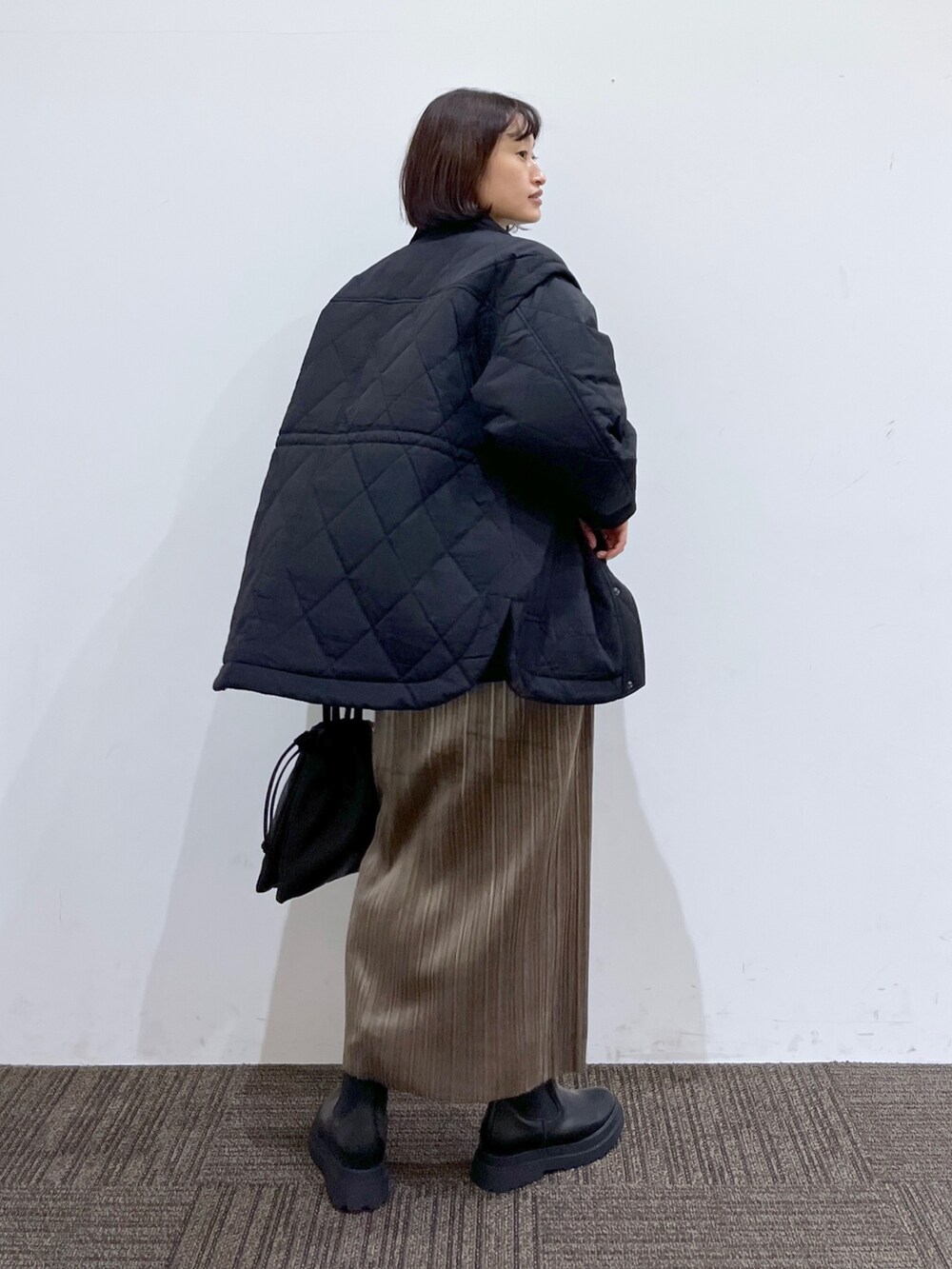 ブラック系のブーツ、ブラック系のショルダーバッグ、ベージュ系のスカートを着用したレディースの秋コーディネートの3枚目の写真