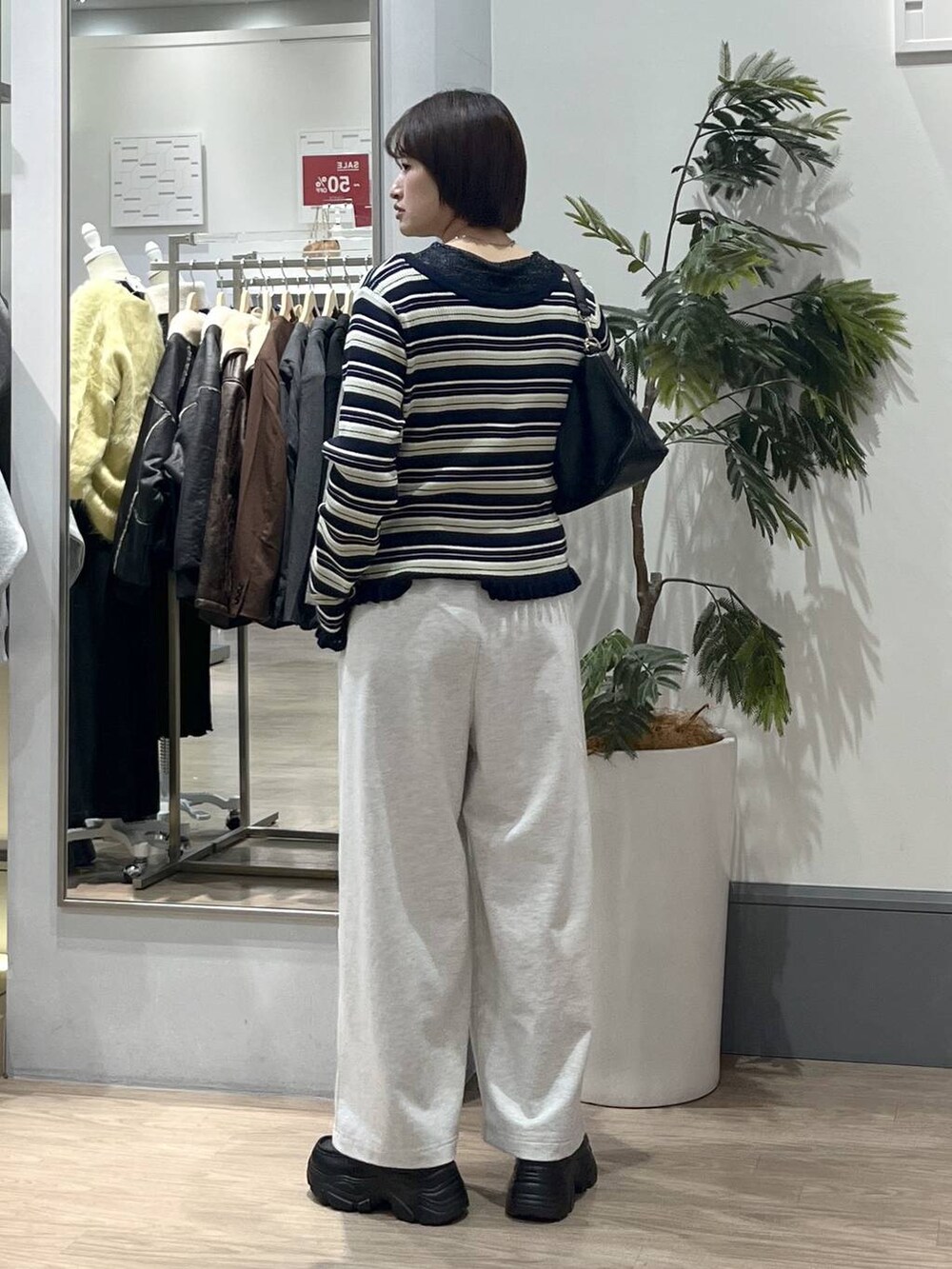 ブラック系のショルダーバッグ、ブラック系のローファー、グレー系のスウェットパンツを着用したレディースの冬コーディネートの4枚目の写真