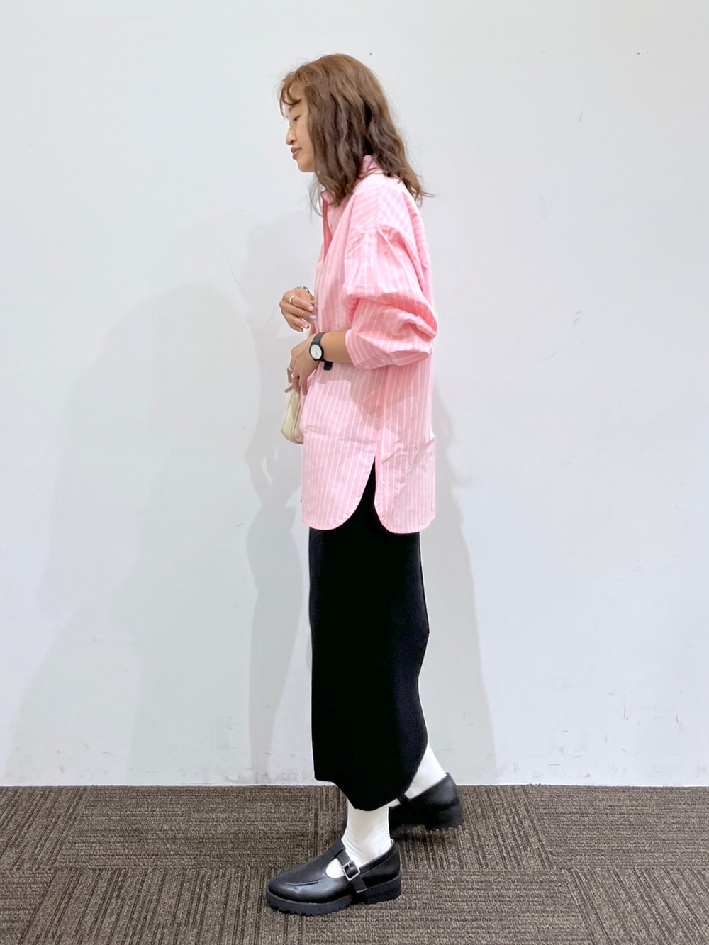 ブラック系のスカート、ホワイト系のショルダーバッグ、ピンク系のシャツ/ブラウスを着用したレディースの秋コーディネートの2枚目の写真