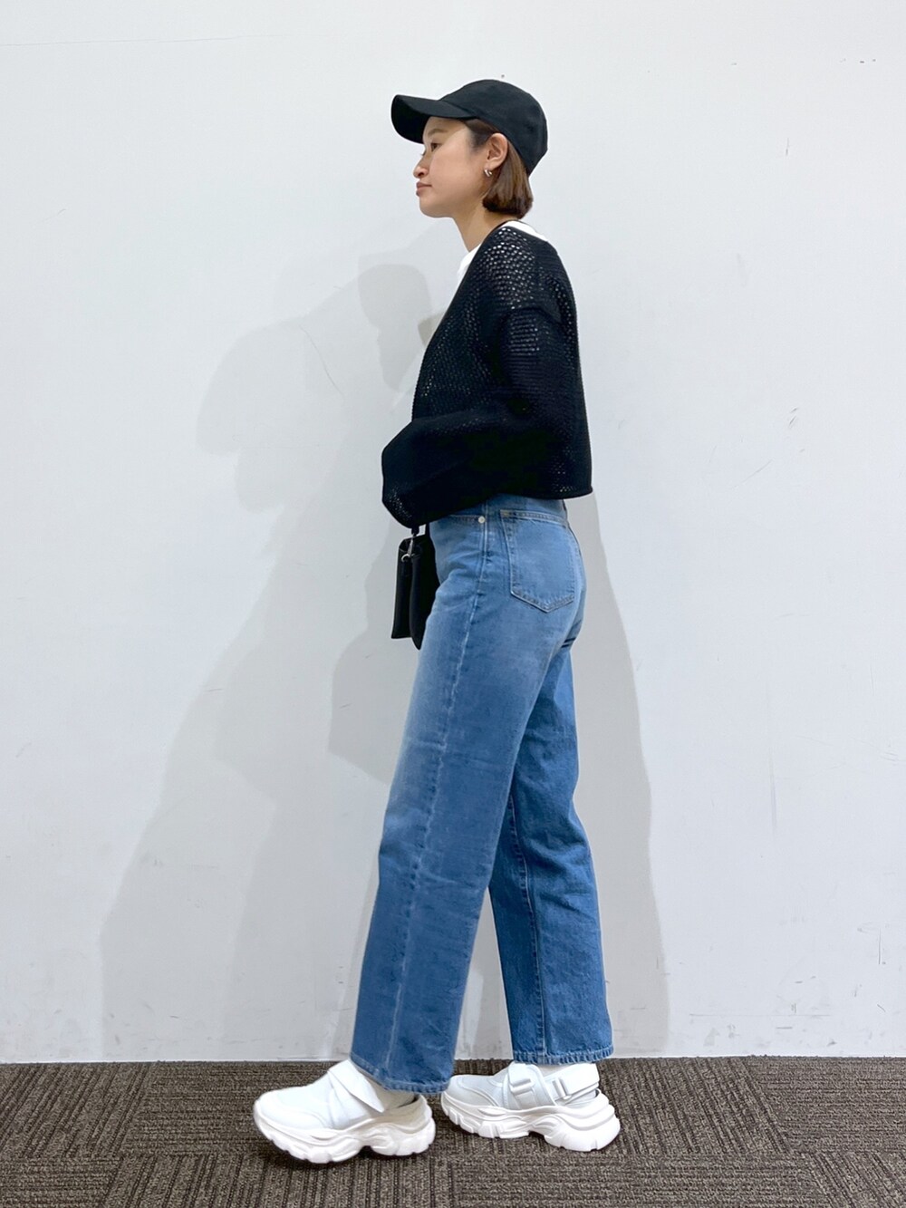 ブラック系のワンピース、ホワイト系のバッグ、ブルー系のパンツを着用したレディースの春コーディネートの2枚目の写真