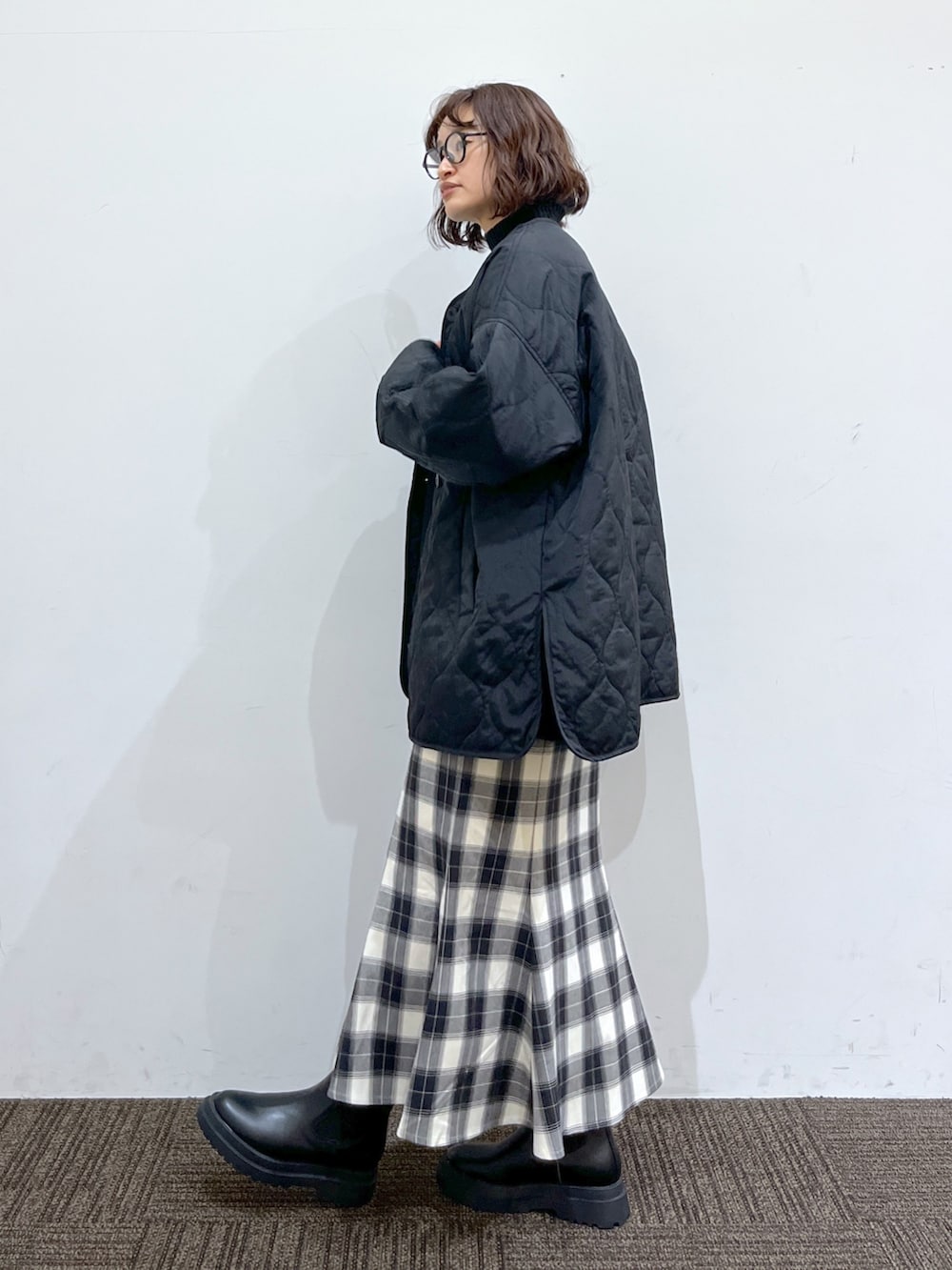 ブラック系のブーツ、ホワイト系のショルダーバッグ、ブラック系のスカートを着用したレディースの冬コーディネートの2枚目の写真