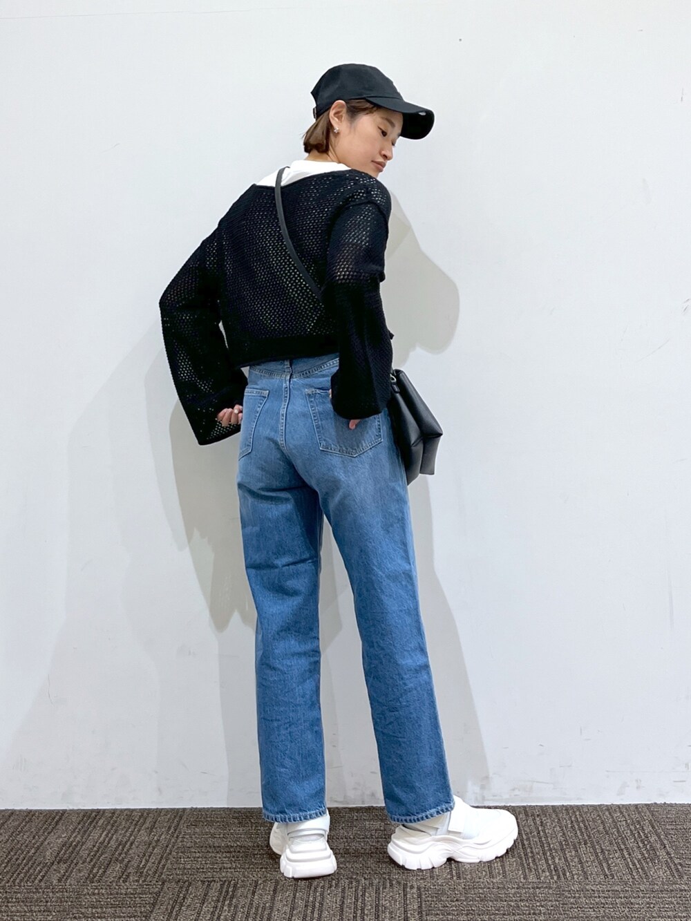 ブラック系のワンピース、ホワイト系のバッグ、ブルー系のパンツを着用したレディースの春コーディネートの3枚目の写真