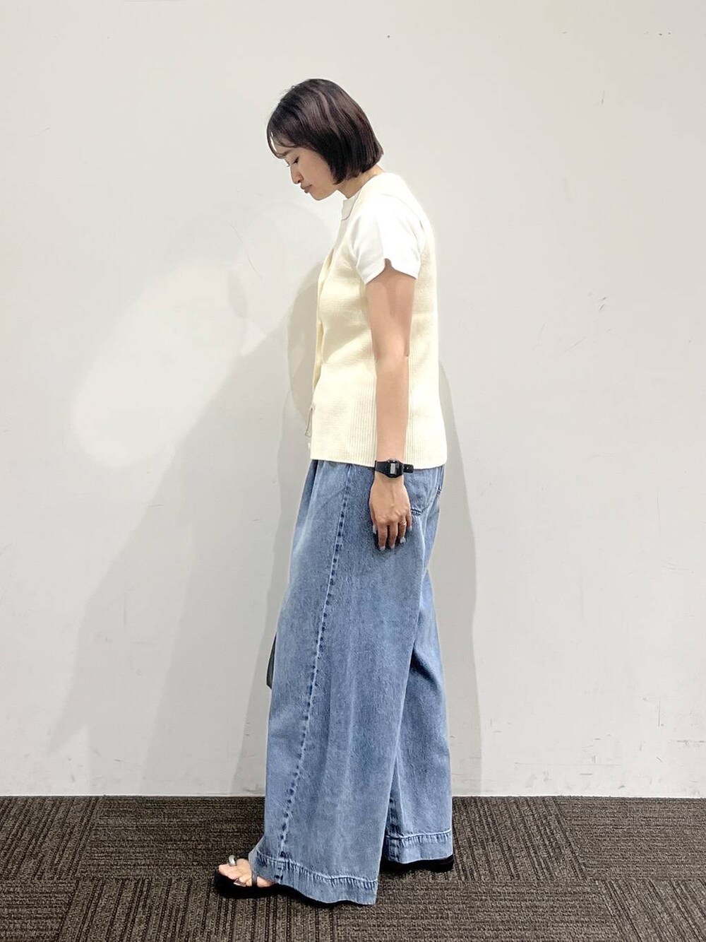 ブルー系のデニムパンツ、ホワイト系のTシャツ/カットソー、ブラック系のサンダルを着用したレディースの夏コーディネートの4枚目の写真