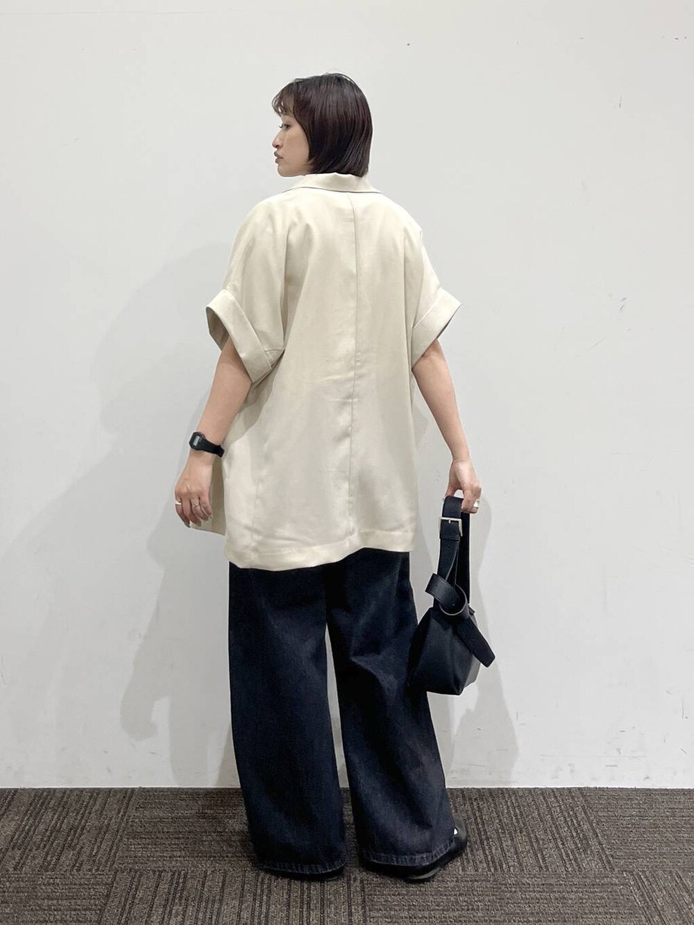 ブラック系のパンプス、ブラック系のデニムパンツ、ホワイト系のテーラードジャケットを着用したレディースの春コーディネートの4枚目の写真