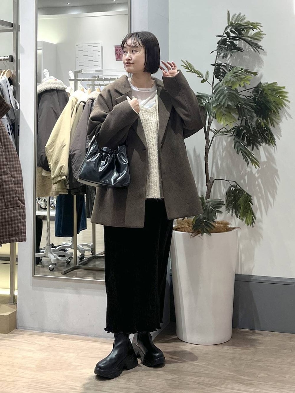 ホワイト系のニット/セーター、ブラック系のブーツ、ブラック系のスカートを着用したレディースの冬コーディネートの2枚目の写真