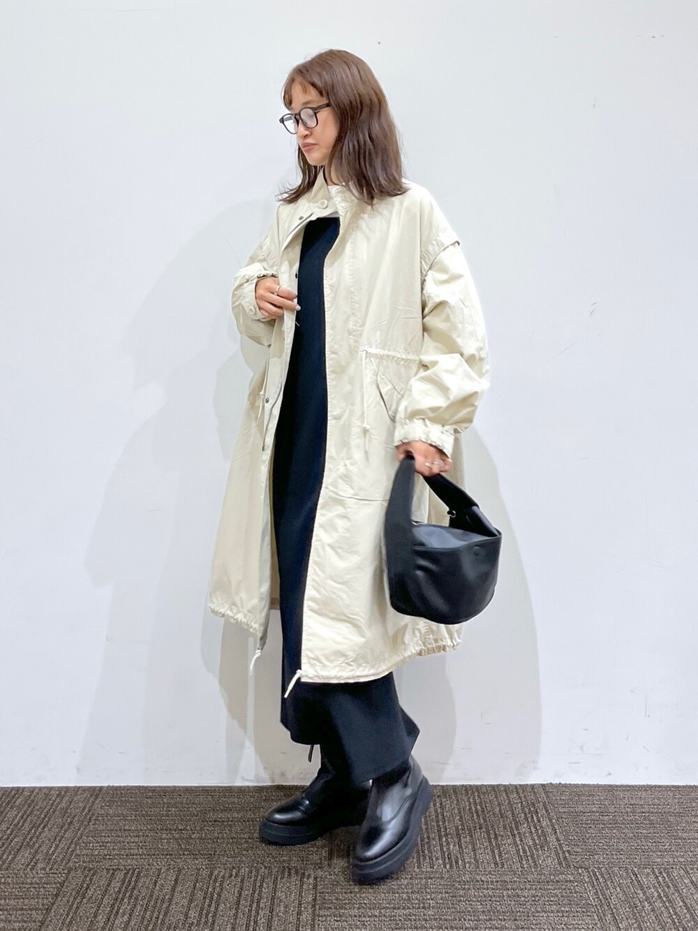 ブラック系のブーツ、ブラック系のバッグ、ブラック系のワンピースを着用したレディースの秋コーディネートの3枚目の写真