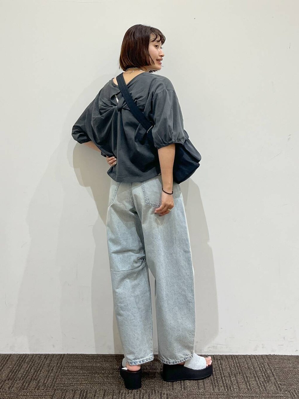 シルバー系のサンダル、ブラック系のショルダーバッグ、ブルー系のデニムパンツを着用したレディースの夏コーディネートの2枚目の写真