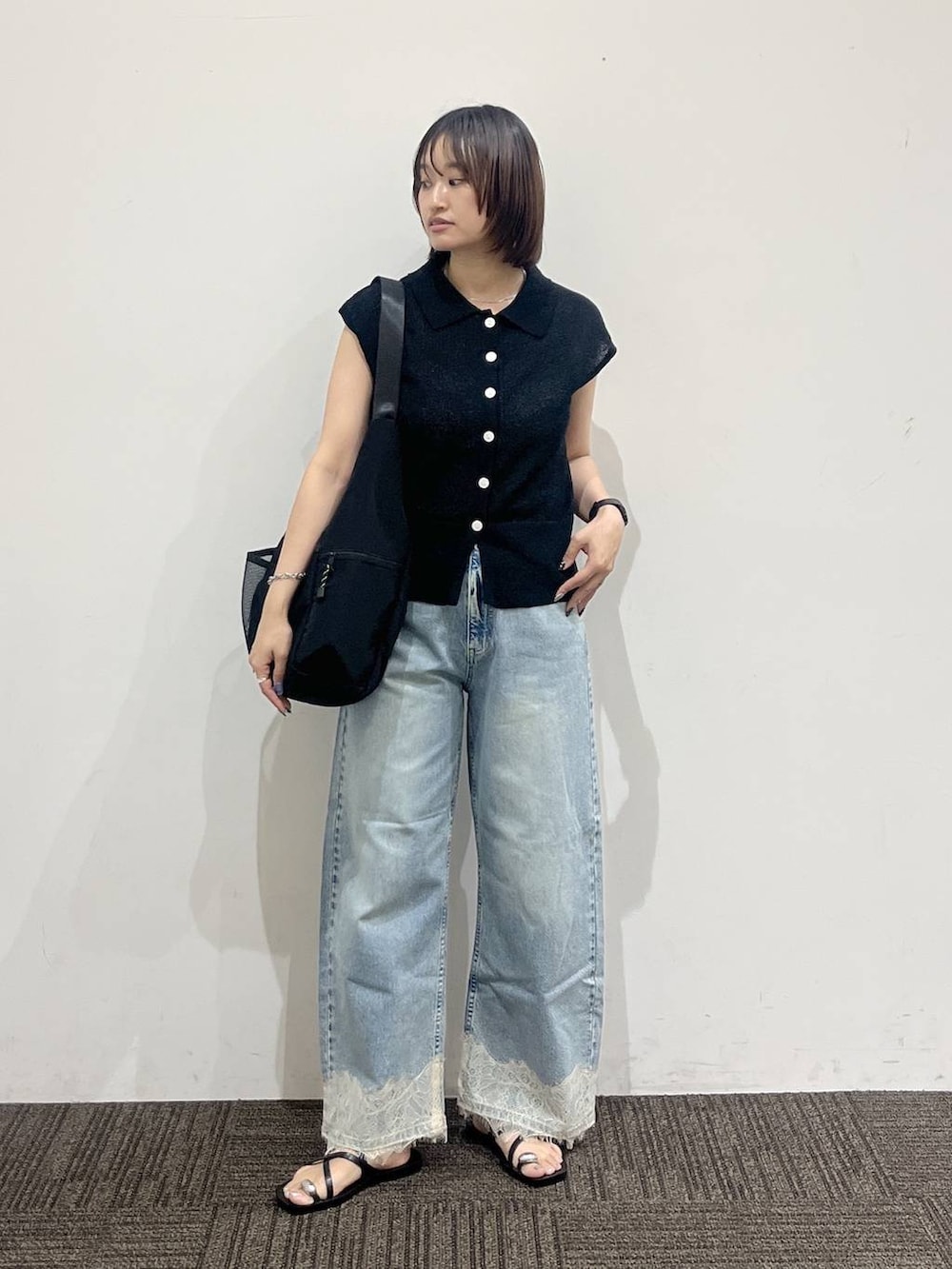 ブラック系のショルダーバッグ、ブラック系のベスト、ブルー系のデニムパンツを着用したレディースの夏コーディネートの2枚目の写真