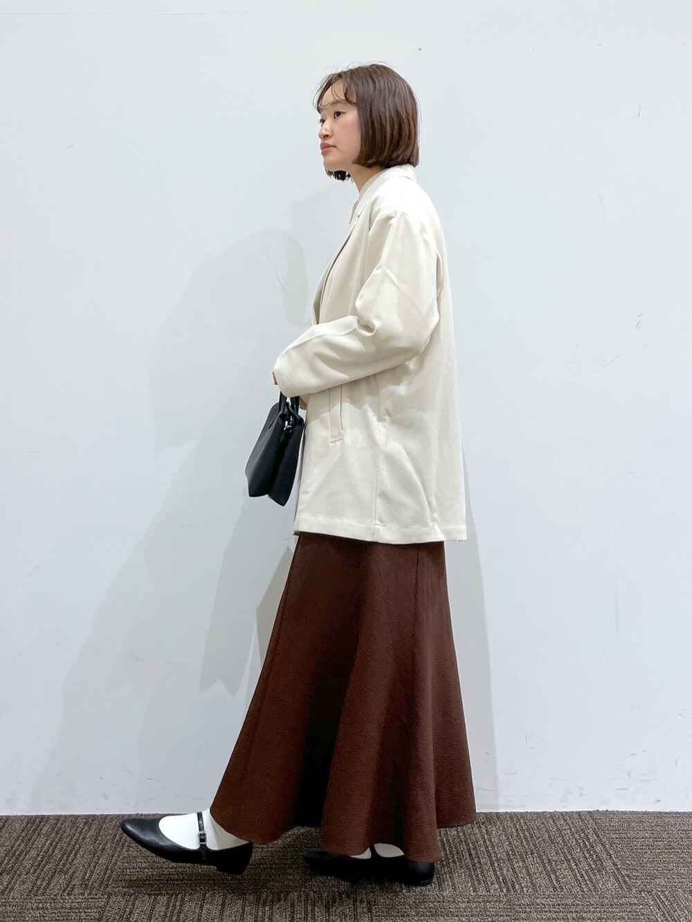 ホワイト系のジャケット/アウター、ホワイト系のトップス、ブラウン系のスカートを着用したレディースの春コーディネートの2枚目の写真