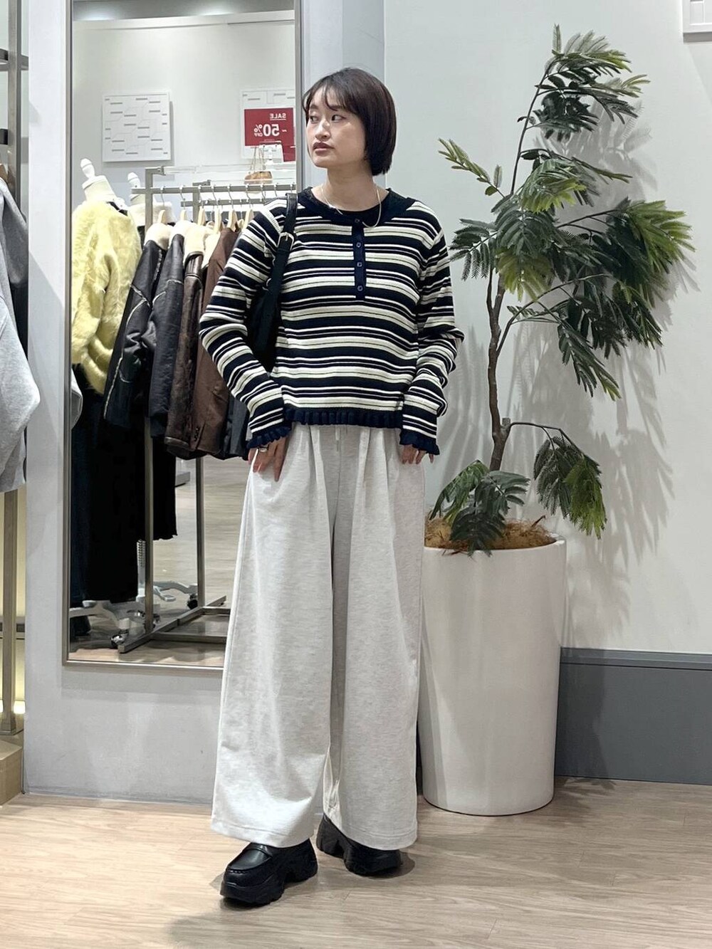 ブラック系のショルダーバッグ、ブラック系のローファー、グレー系のスウェットパンツを着用したレディースの冬コーディネートの2枚目の写真