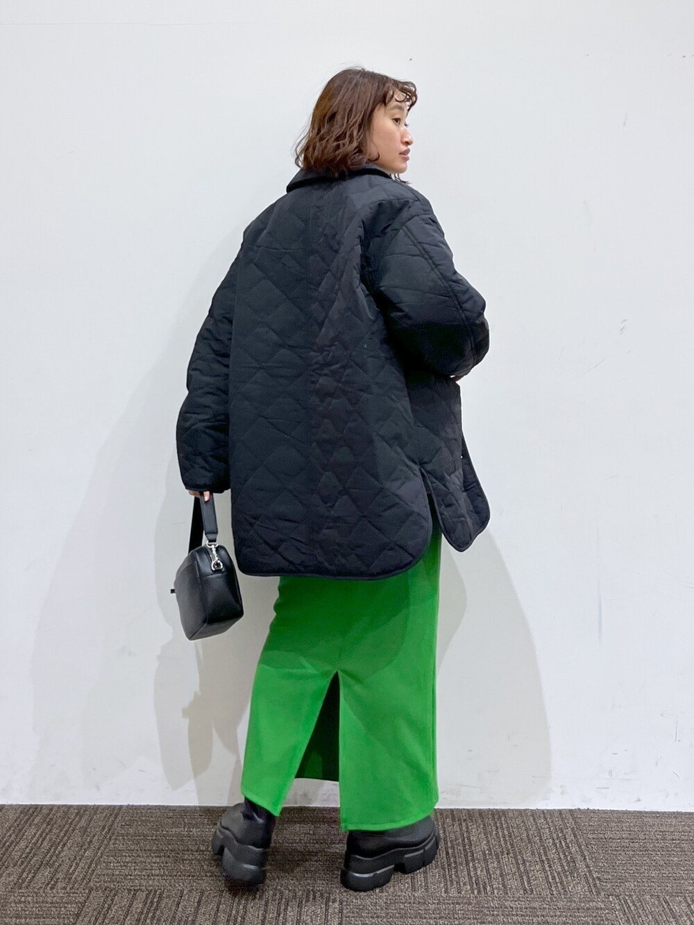 ブラック系のミリタリージャケット、ホワイト系のニット/セーター、グリーン系のスカートを着用したレディースの冬コーディネートの3枚目の写真