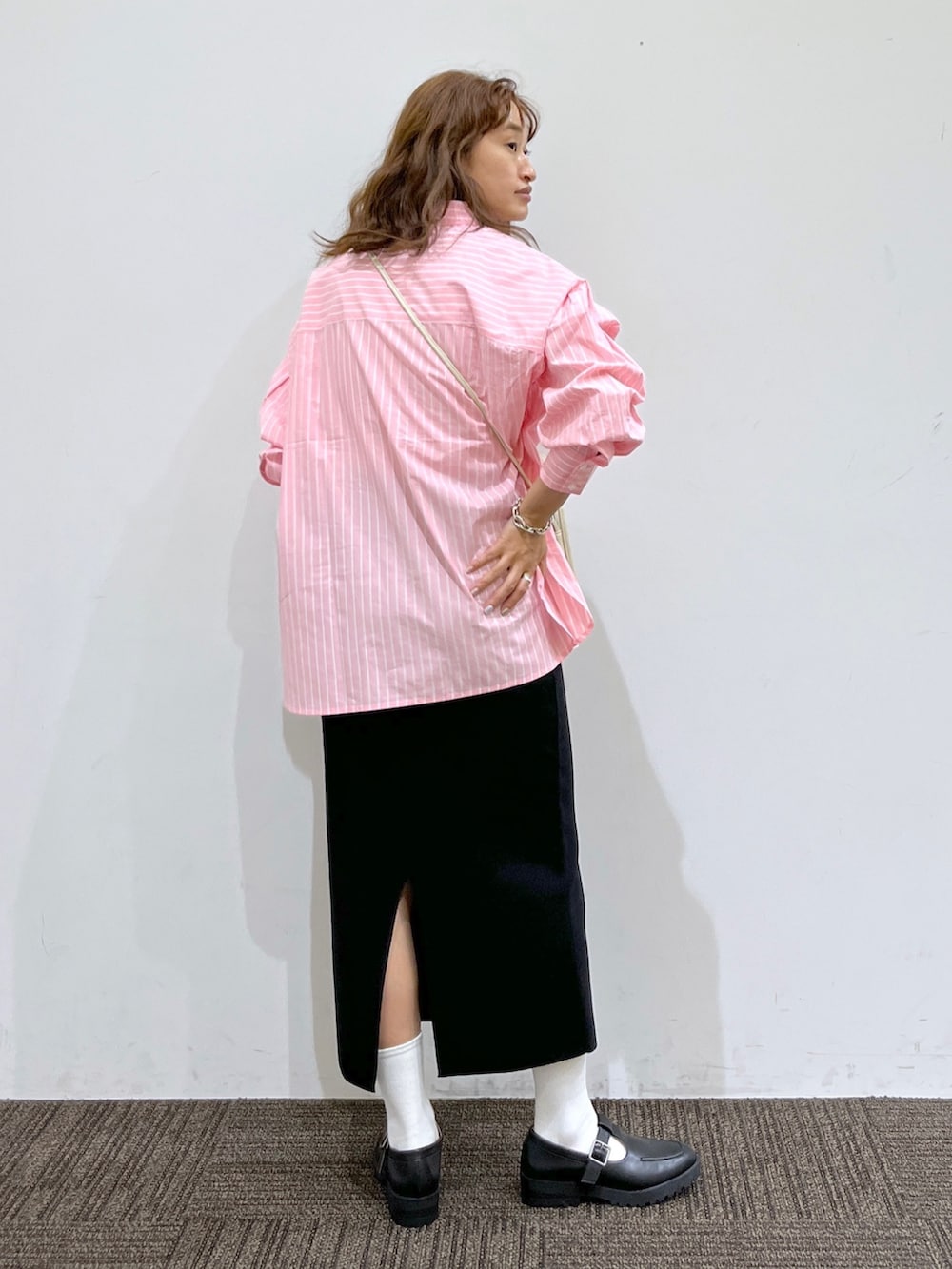 ブラック系のスカート、ホワイト系のショルダーバッグ、ピンク系のシャツ/ブラウスを着用したレディースの秋コーディネートの3枚目の写真