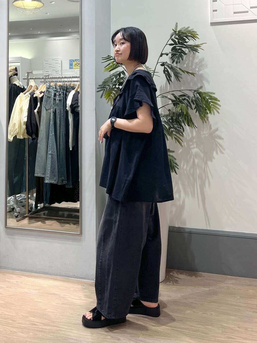 ブラック系のサンダル、ブラック系のデニムパンツ、ブラック系のショルダーバッグを着用したレディースの春コーディネートの4枚目の写真