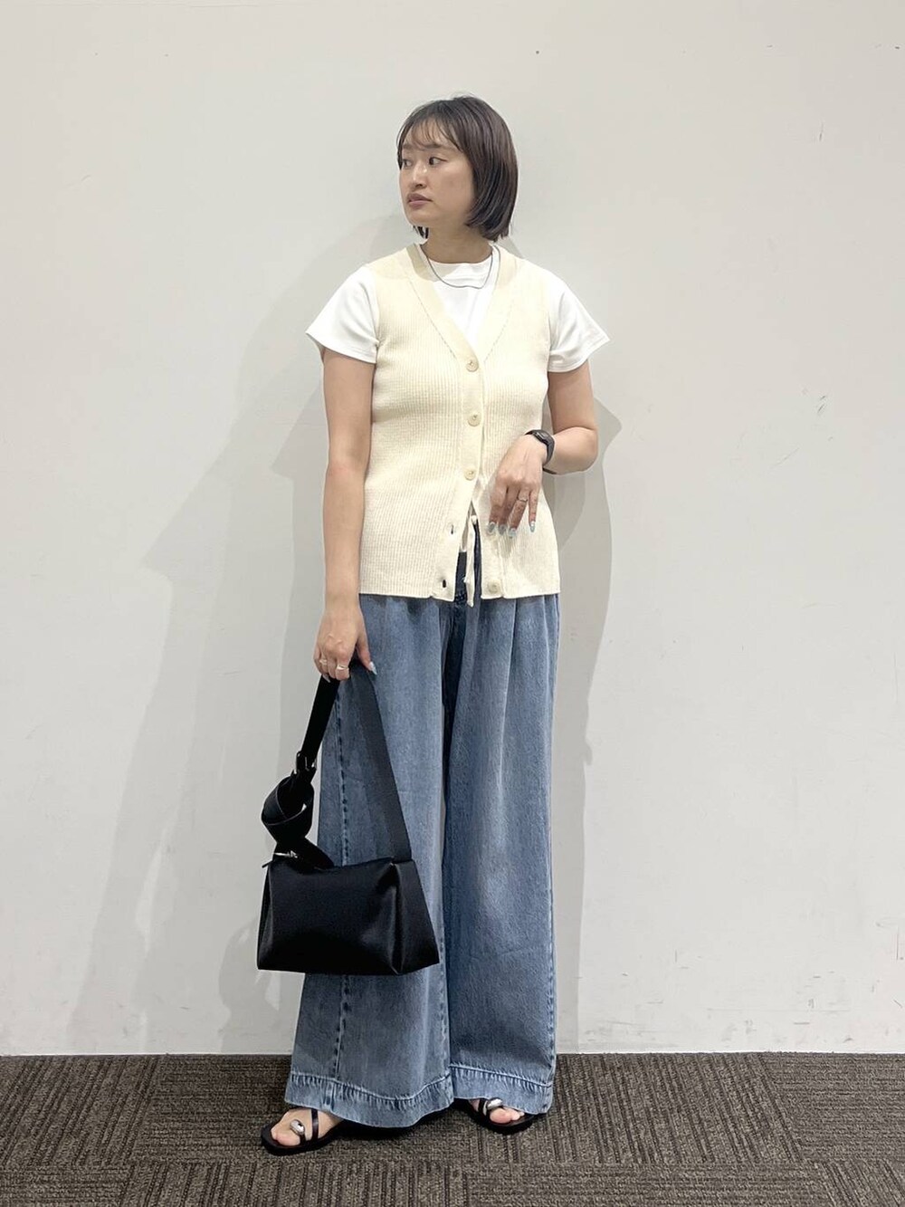 ブルー系のデニムパンツ、ホワイト系のTシャツ/カットソー、ブラック系のサンダルを着用したレディースの夏コーディネートの2枚目の写真