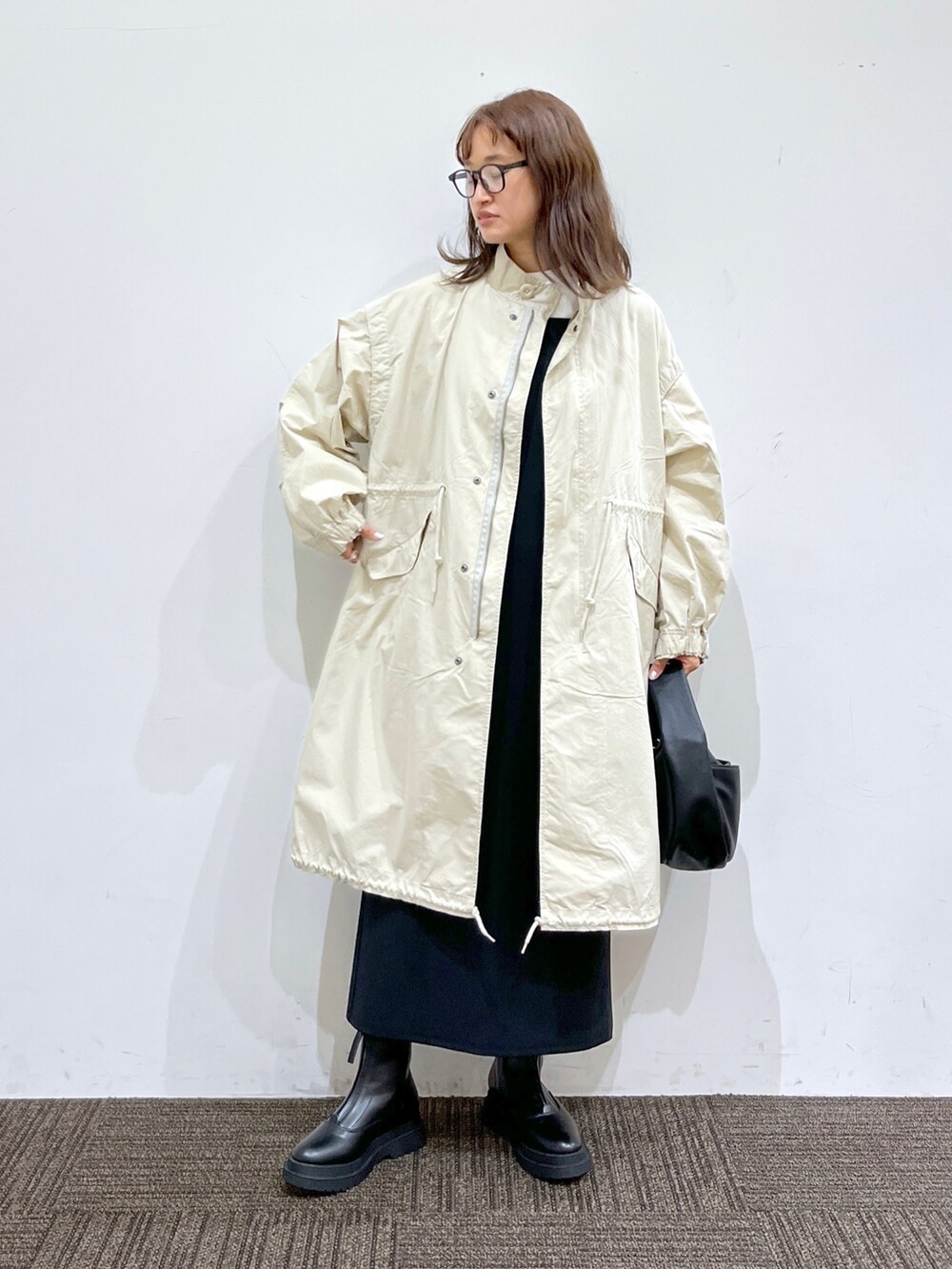 ブラック系のブーツ、ブラック系のバッグ、ブラック系のワンピースを着用したレディースの秋コーディネートの2枚目の写真