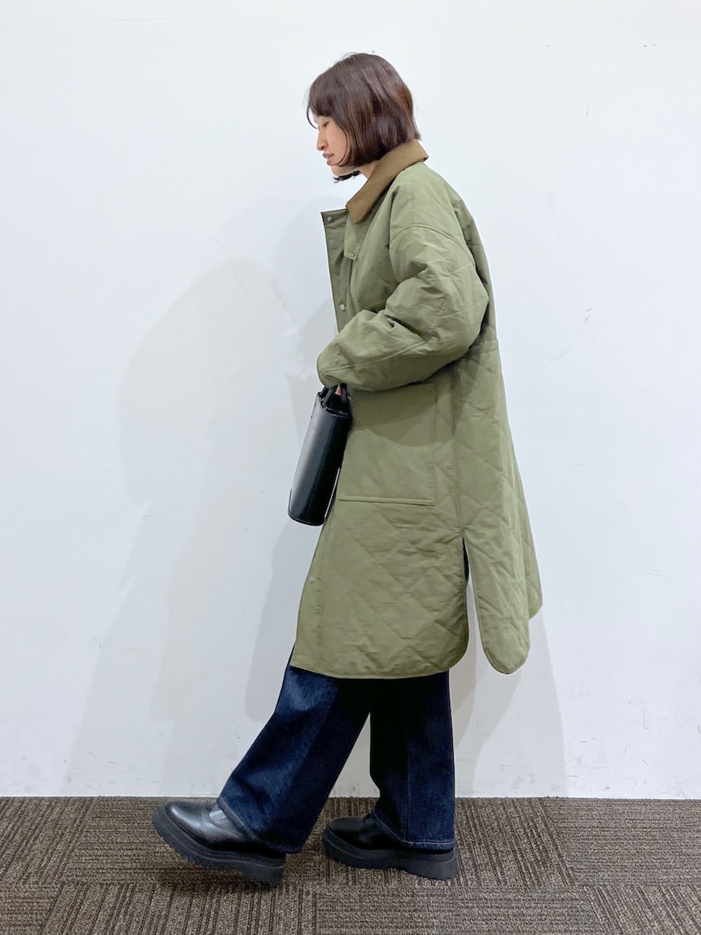 グレー系のトップス、グリーン系のジャケット/アウター、ブルー系のパンツを着用したレディースの秋コーディネートの2枚目の写真