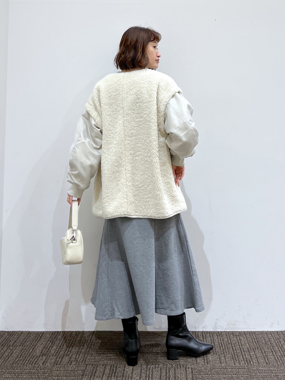 ホワイト系のブルゾン、グレー系のワンピース、ブラック系のブーツを着用したレディースの冬コーディネートの3枚目の写真