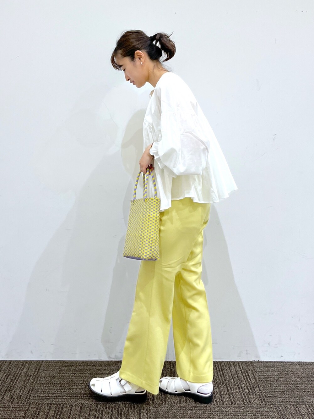 イエロー系のスラックス、パープル系のかごバッグ、ホワイト系のシャツ/ブラウスを着用したレディースの春コーディネートの2枚目の写真
