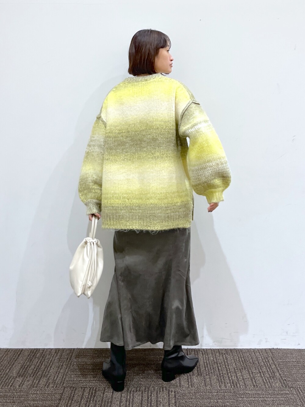 ブラック系のブーツ、ホワイト系のバッグ、グレー系のスカートを着用したレディースの秋コーディネートの3枚目の写真