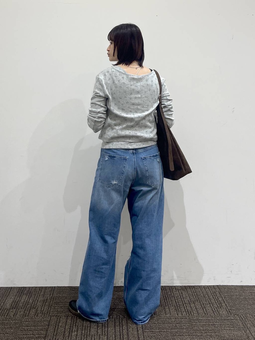 グレー系のTシャツ/カットソー、ブラウン系のショルダーバッグ、ブルー系のデニムパンツを着用したレディースの秋コーディネートの4枚目の写真