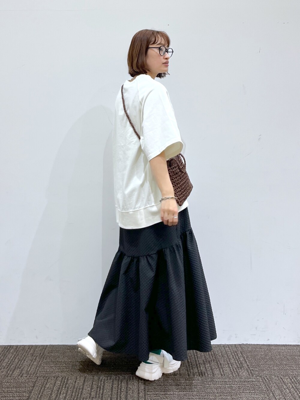 ホワイト系のTシャツ/カットソー、ブラック系のスカート、ゴールド系のバッグを着用したレディースの春コーディネートの3枚目の写真