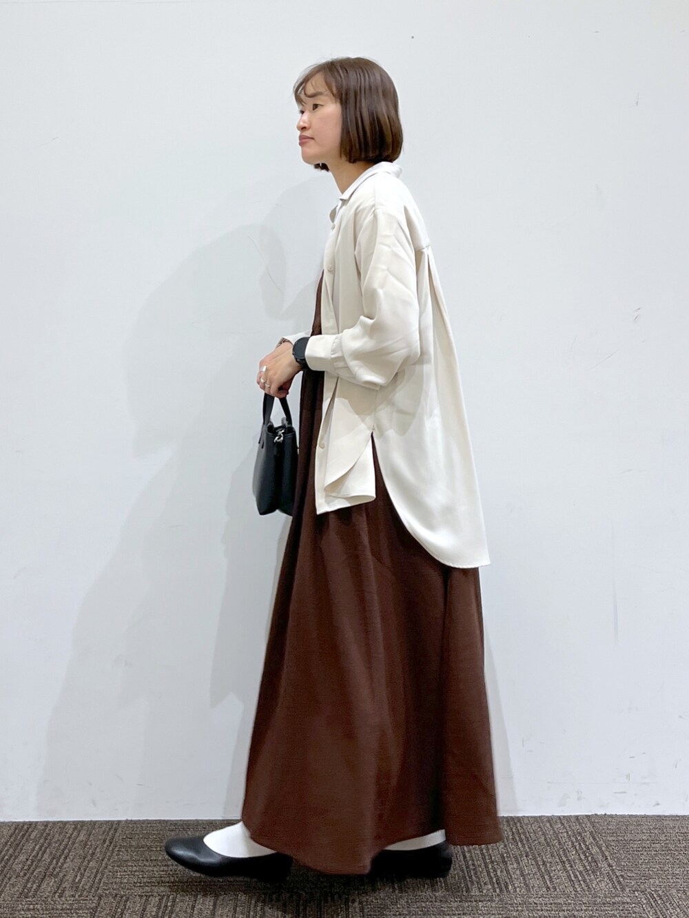 ベージュ系のトップス、ホワイト系のTシャツ/カットソー、ブラウン系のワンピース/ドレスを着用したレディースの春コーディネートの2枚目の写真