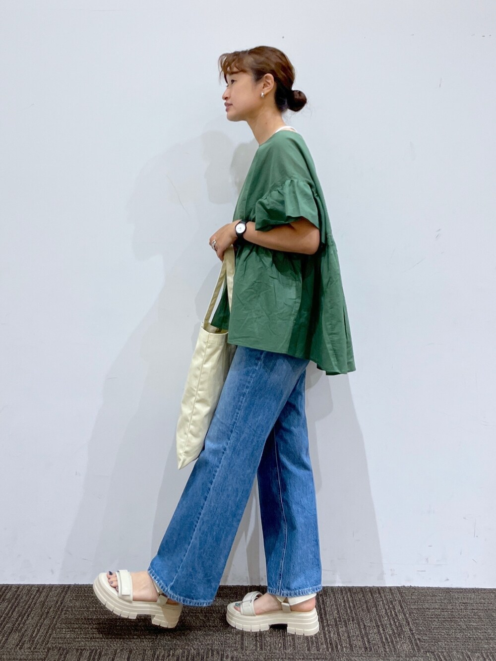 ブルー系のデニムパンツ、ホワイト系のトートバッグ、グリーン系のシャツ/ブラウスを着用したレディースの夏コーディネートの2枚目の写真
