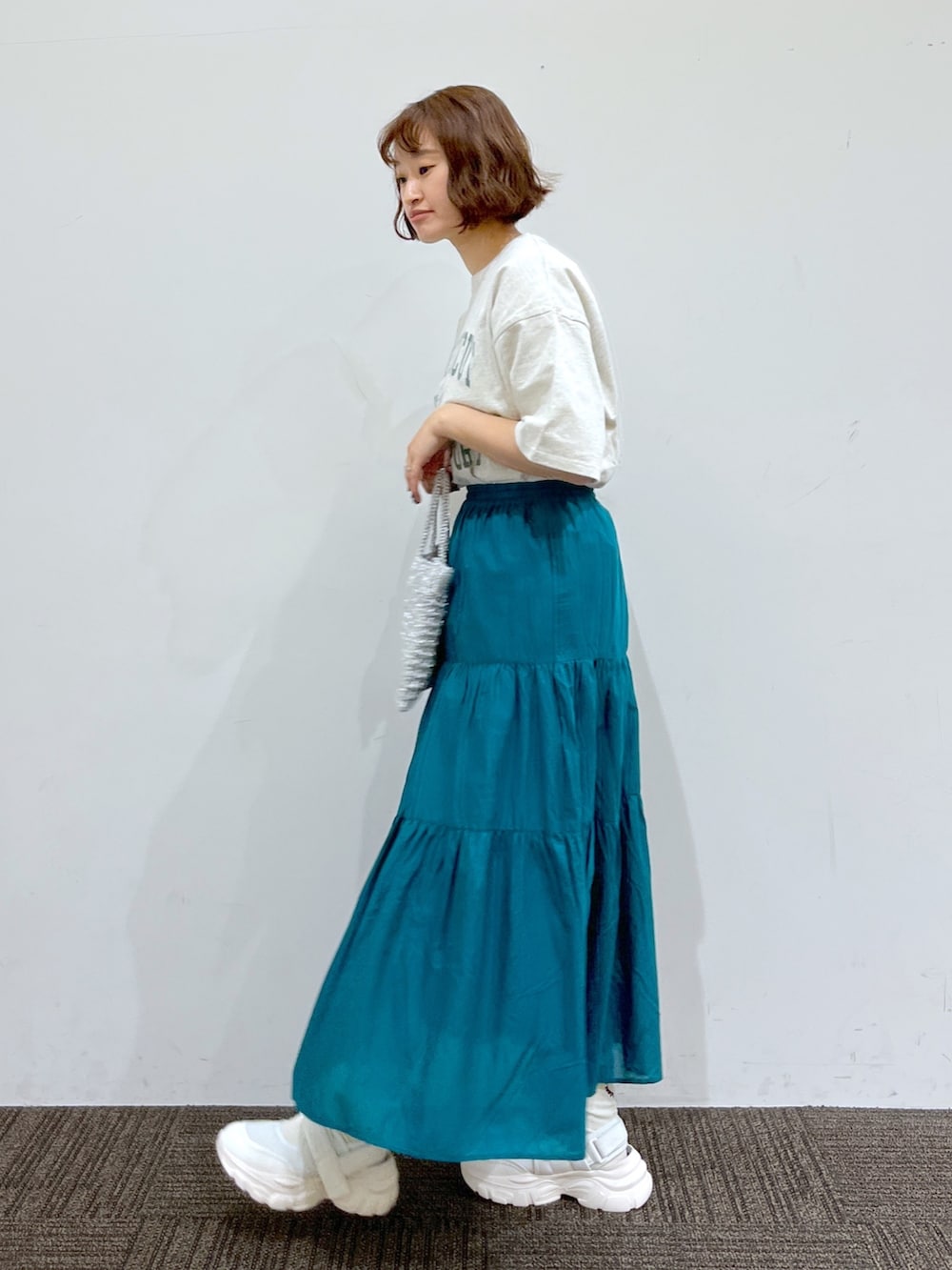 グレー系のTシャツ/カットソー、グリーン系のスカート、シルバー系のバッグを着用したレディースの春コーディネートの2枚目の写真