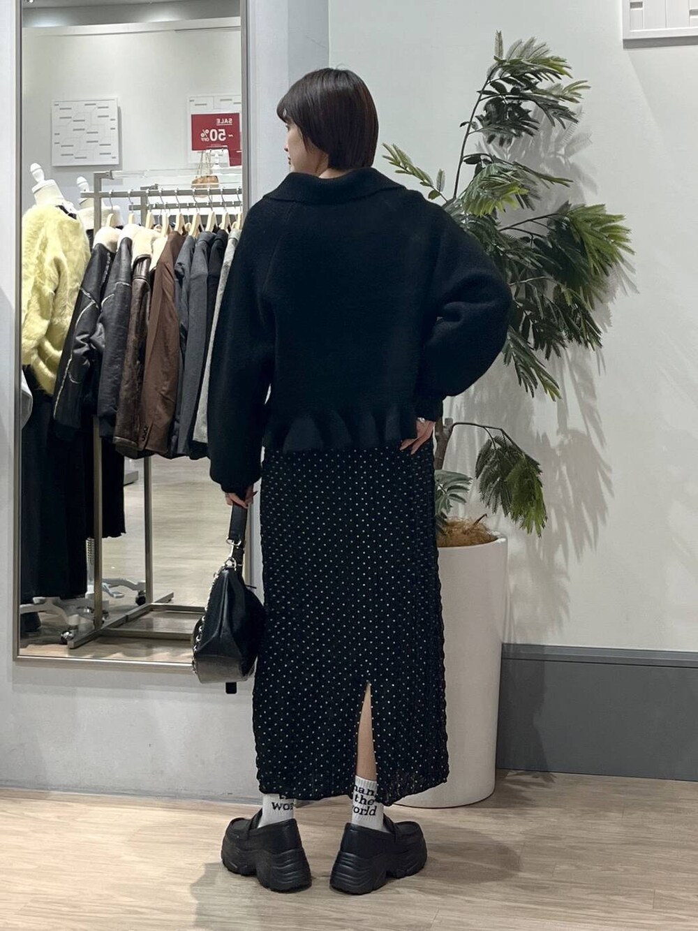 ブラック系のショルダーバッグ、ブラック系のローファー、ブラック系のスカートを着用したレディースの冬コーディネートの5枚目の写真