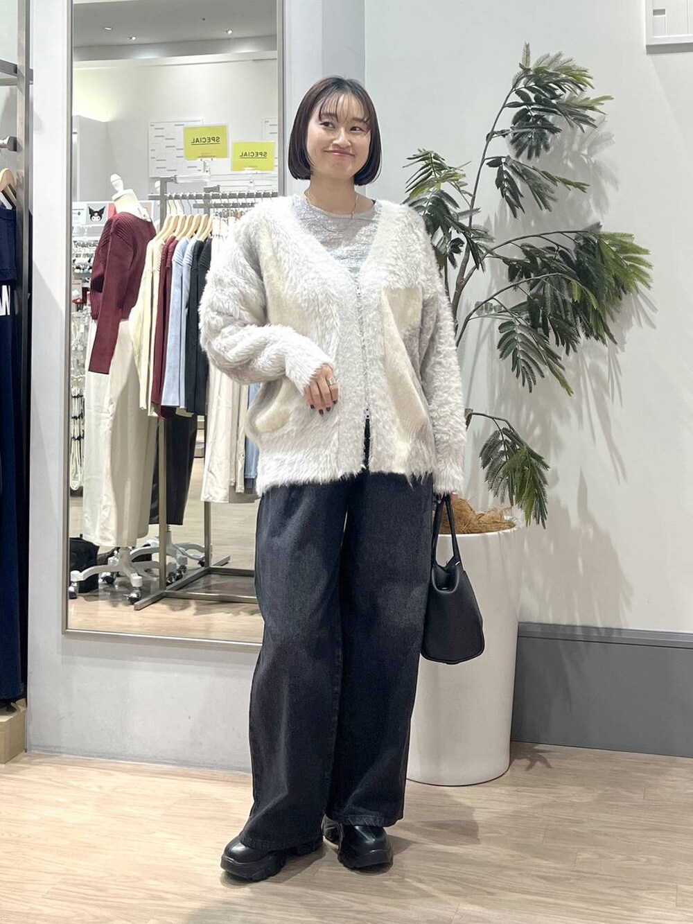 ブラック系のブーツ、ホワイト系のカーディガン/ボレロ、ホワイト系のTシャツ/カットソーを着用したレディースの秋コーディネートの3枚目の写真