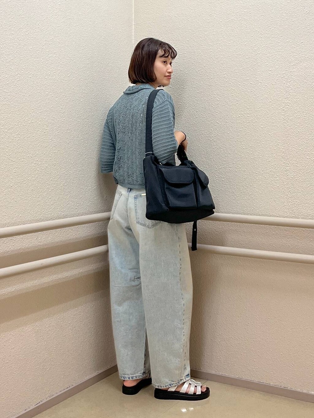 ブルー系のデニムパンツ、グリーン系のニット/セーター、シルバー系のスニーカーを着用したレディースの夏コーディネートの4枚目の写真