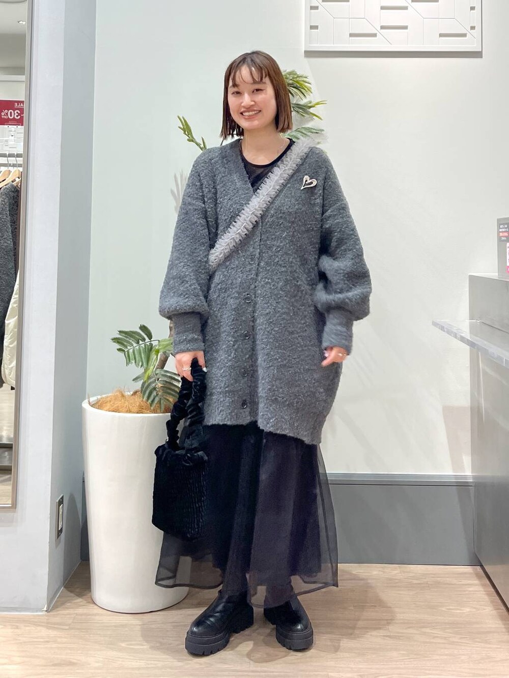 グレー系のチュニック、ブラック系のブーツ、ブラック系のショルダーバッグを着用したレディースの冬コーディネートの2枚目の写真