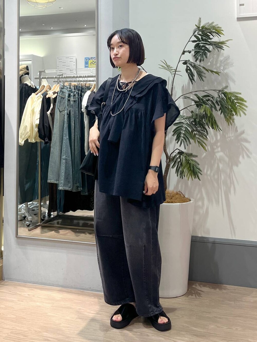 ブラック系のサンダル、ブラック系のデニムパンツ、ブラック系のショルダーバッグを着用したレディースの春コーディネートの3枚目の写真