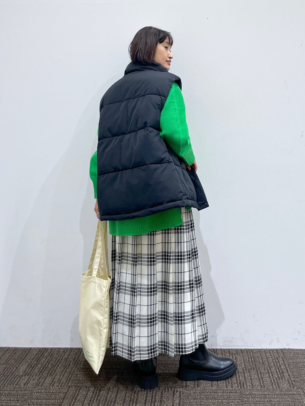 ブラック系のブーツ、ホワイト系のバッグ、ホワイト系のスカートを着用したレディースの秋コーディネートの4枚目の写真