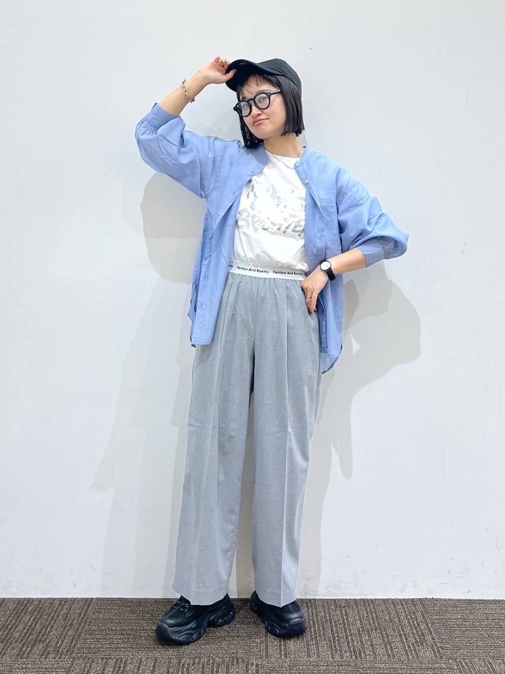 グレー系のスラックス、ブラック系のスニーカー、ホワイト系のTシャツ/カットソーを着用したレディースの春コーディネートの2枚目の写真