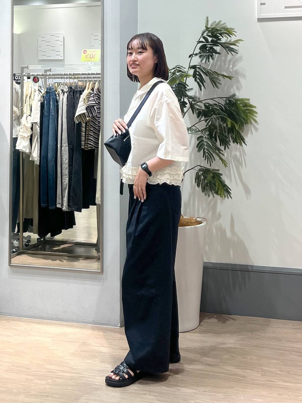 ブラック系のサンダル、ホワイト系のシャツ/ブラウス、ブラック系のショルダーバッグを着用したレディースの夏コーディネートの3枚目の写真