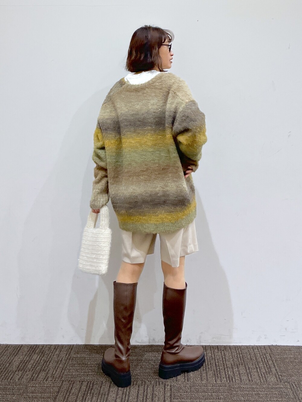 ホワイト系のトートバッグ、イエロー系のトップス、ホワイト系のトップスを着用したレディースの冬コーディネートの3枚目の写真